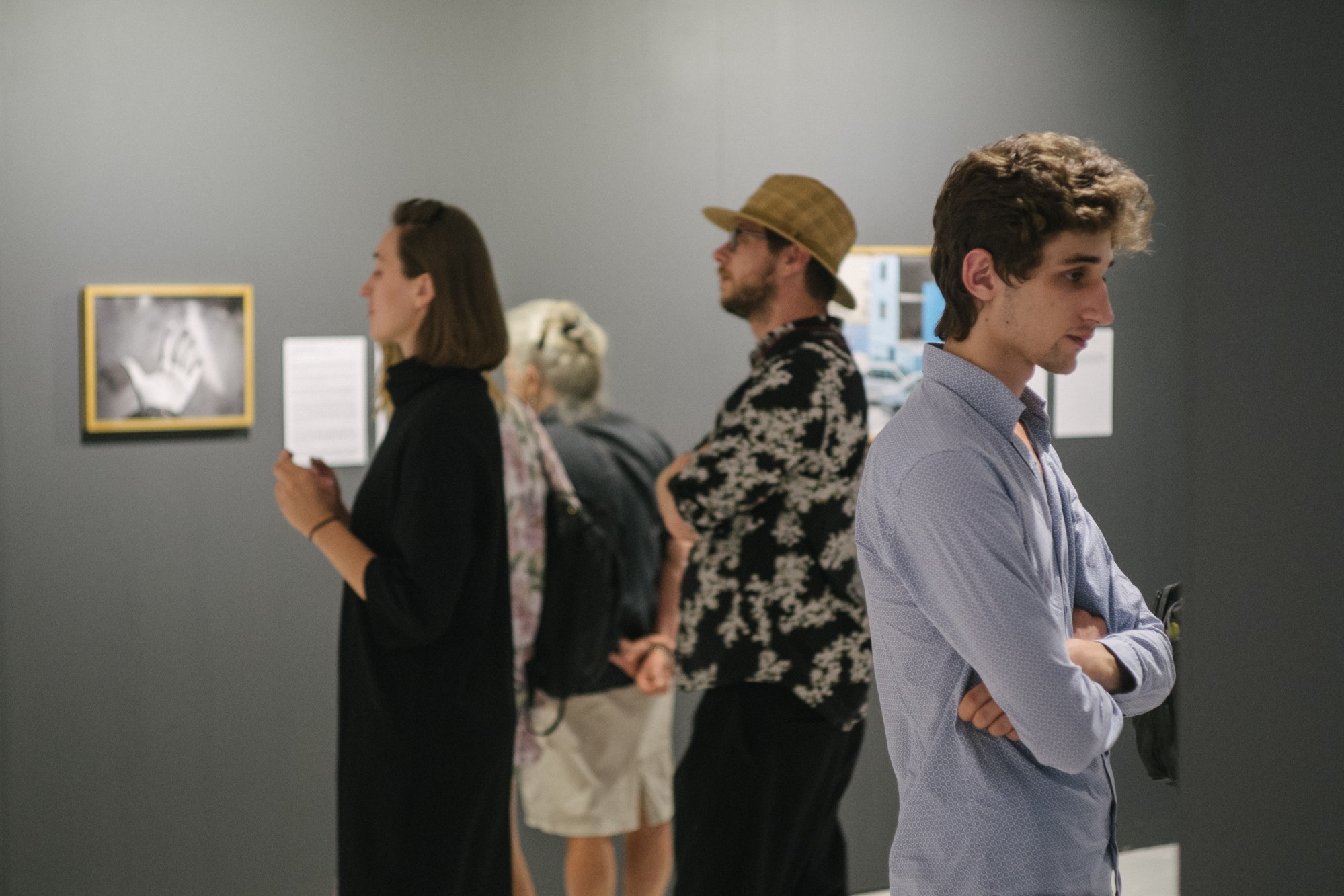 Grupa odwiedzających zgromadzona w przestrzeni wystawowej.